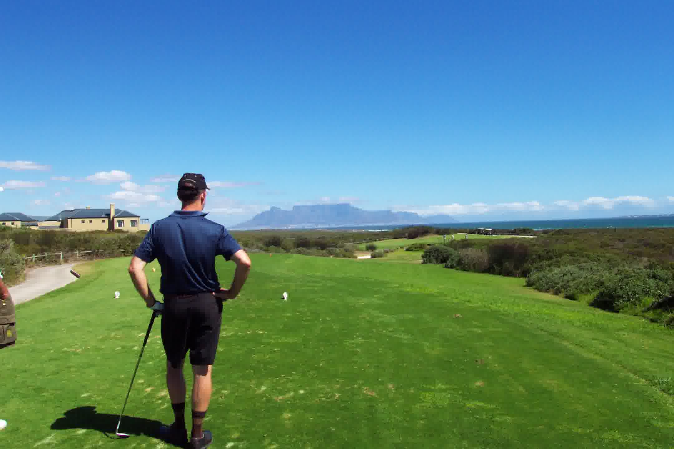 Golfer on a coastal fairway in South Africa with the ocean and mountains beyond